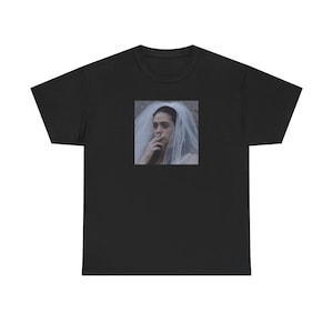 May include: Black t-shirt with a square image of a person in a bridal veil smoking a cigarette. The image is in the centre of the shirt. The person in the image has dark hair and is looking to the side.
