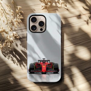 May include: A smartphone case with a red Formula 1 race car design. The case has a light grey background and a glossy finish. The race car is detailed with black and yellow accents.