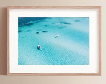 Könnte beinhalten: Eine Luftaufnahme von zwei Segelbooten, die in einem türkisblauen Meer vor Anker liegen. Das Wasser ist klar und flach, an einigen Stellen ist der sandige Boden sichtbar.