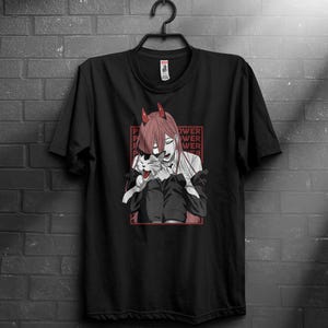 Könnte beinhalten: Schwarzes T-Shirt mit einem rothaarigen Anime-Charakter mit Hörnern, der eine Katze hält. Die Grafik enthält das Wort "POWER" in Rot. Das Design ist in einem roten Rechteck eingerahmt.