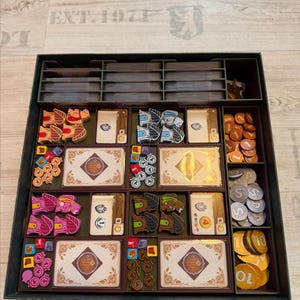 May include: A board game organizer with various components, including cards, wooden tokens, and coins. The organizer is divided into compartments, with different colored pieces and cards. The text "EXT. 1971" is visible on the surface.