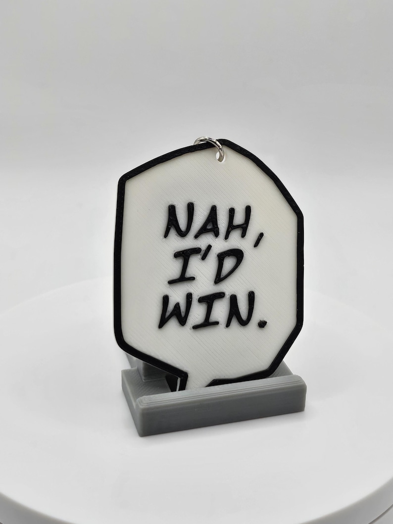 May include: White speech bubble keychain with black outline and text that reads "NAH, I'D WIN."