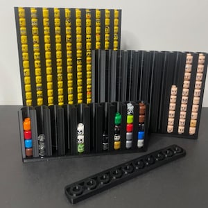 May include: Black 3D-printed organizers displaying various Lego minifigure heads and accessories. The organizers are designed to hold and showcase the Lego pieces, with different sections for various types of heads and accessories.