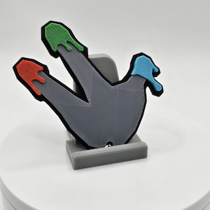 May include: A gray 3D printed foot with three toes, each with a different colored cap. The toes are green, red, and blue. The foot is on a gray stand.