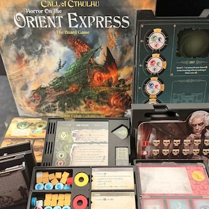 May include: A Call of Cthulhu Horror on the Orient Express board game set featuring a large illustrated box, black plastic component organizers, various game cards with text, and small colored wooden tokens in yellow, blue, and red shades.