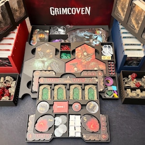 May include: A board game organizer with various components, including cards, tokens, and game pieces. The organizer is black and red, with the game title "Grimcoven" displayed prominently. The game pieces are in various colors.