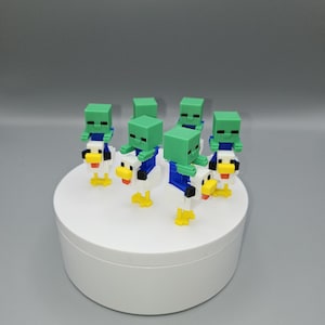 May include: A collection of five small plastic figurines featuring blocky green zombie characters riding on top of white chickens with yellow beaks and feet. Each figure has a pixelated design with blue accents on the zombie torso and black eyes.