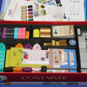 May include: A board game box titled Container, containing various game components including colorful plastic ship miniatures, small gold-colored rectangular tokens, a deck of cards labeled Loan, and several illustrated cardboard player boards.