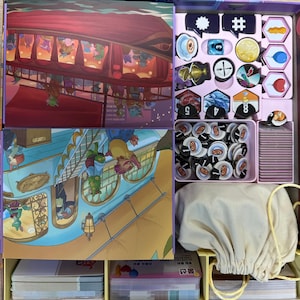 May include: Open board game box with colorful illustrations. The box contains game cards, tokens, and a drawstring bag. The artwork depicts a fantasy setting with airships and whimsical characters. The game pieces are organized in compartments.