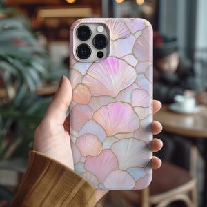 May include: A white iPhone case with a pink and white floral pattern. The case has a raised camera bump and a clear back.