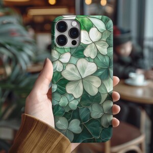 May include: A green and white phone case with a four-leaf clover design. The case is made of a durable material and has a sleek, modern look.