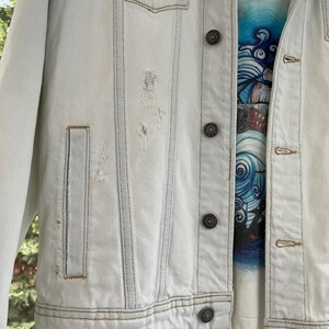 Puede incluir: Una chaqueta vaquera azul claro con detalles desgastados y varios bolsillos. La chaqueta tiene cierre de botones y un estilo cl&aacute;sico.