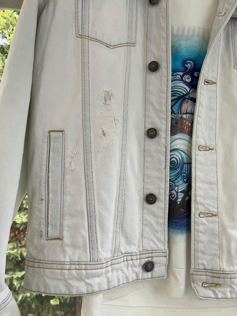 Puede incluir: Una chaqueta vaquera azul claro con detalles desgastados y varios bolsillos. La chaqueta tiene cierre de botones y un estilo cl&aacute;sico.