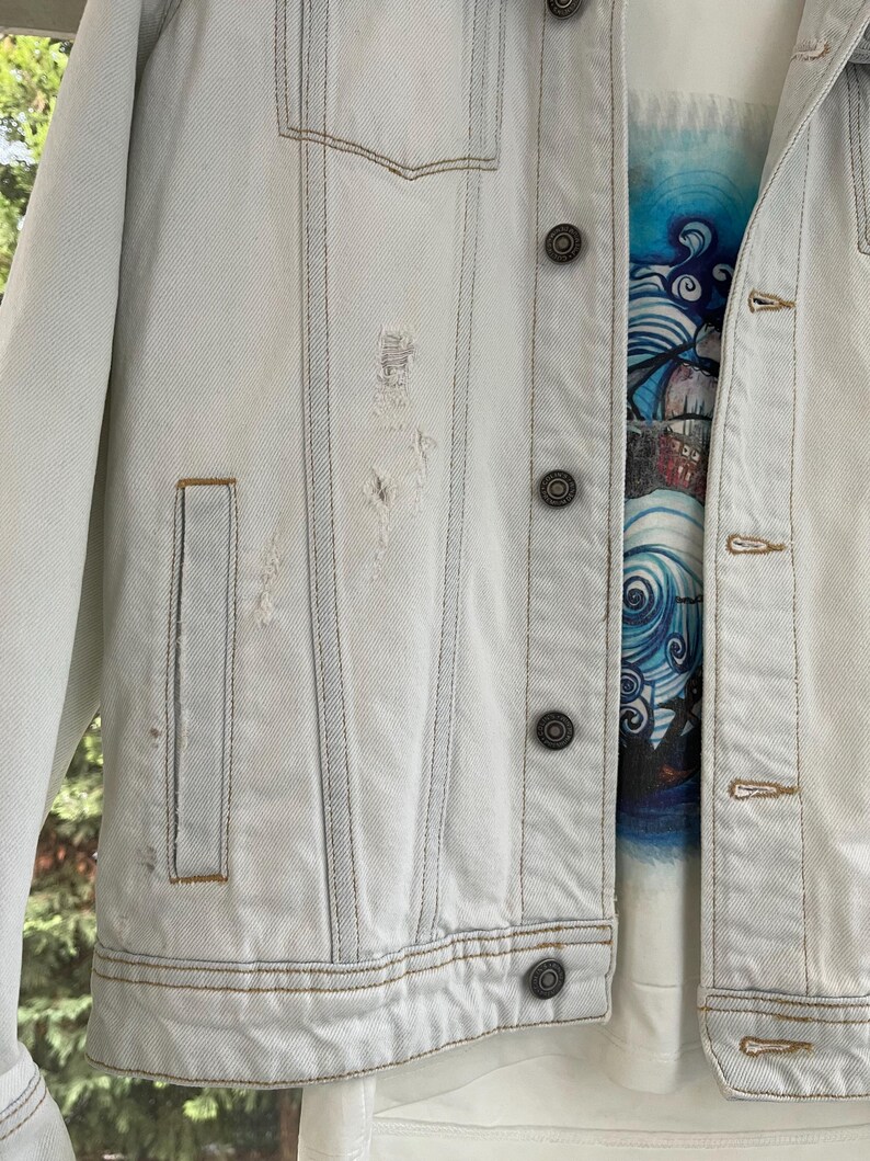 Puede incluir: Una chaqueta vaquera azul claro con detalles desgastados y varios bolsillos. La chaqueta tiene cierre de botones y un estilo cl&aacute;sico.