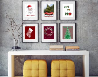 May include: Six framed Christmas-themed prints on a white wall above a white console table with two yellow tufted ottomans. The prints feature a Santa Claus, a Christmas tree, a wreath, a stocking, a car with a Christmas tree on top, and the words "Ho Ho Ho".