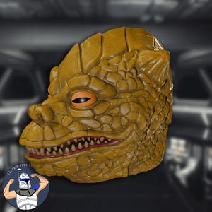 May include: A mustard-yellow lizard mask with textured skin, orange eyes, and a red-lined mouth filled with white teeth. The mask has a reptilian appearance, suitable for cosplay or costume use.