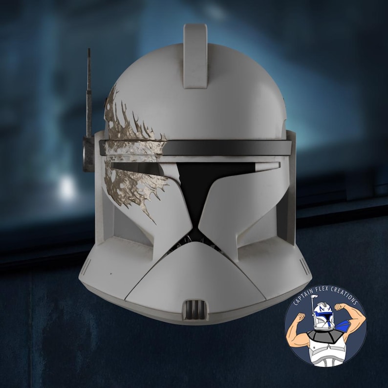 May include: A white and gray Clone Trooper helmet with a black visor and antenna. The helmet has gold-colored weathering details and a rectangular top piece. The image includes a logo in the bottom right corner.