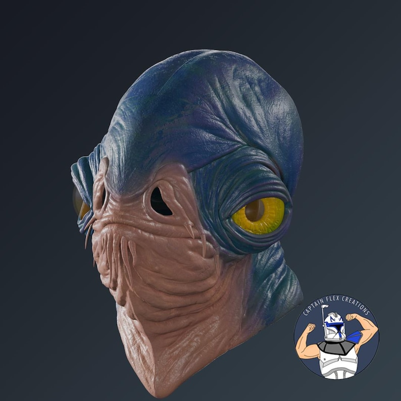 Puede incluir: M&aacute;scara detallada de una criatura alien&iacute;gena con cabeza azul y rostro bronceado. La m&aacute;scara tiene grandes ojos amarillos y una superficie texturizada. Es un objeto impreso en 3D.