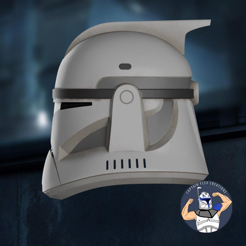 May include: A white and gray helmet with a distinctive design, featuring a raised top and dark gray accents. The helmet has a series of vertical lines on the lower front and a circular detail on the side. The image includes a logo in the lower right corner.