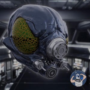 Könnte beinhalten: Ein dunkelblauer und grüner Helm mit einer strukturierten Oberfläche und einer großen, runden, silberfarbenen Lüftung. Der Helm hat ein einziges, großes, grünes Auge mit einem gelben, netzartigen Muster.