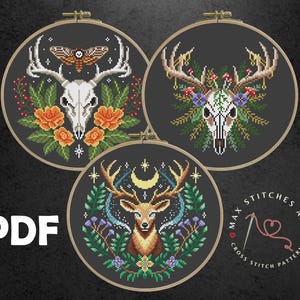 Puede incluir: Tres patrones circulares de bordado que representan una calavera de ciervo con flores, una polilla y una calavera de ciervo con flores, y un ciervo con una luna creciente y estrellas. Los patrones son en blanco y negro con acentos de color. El texto "Max Stitches Art Cross Stitch Patterns" está en un círculo en la parte inferior derecha.