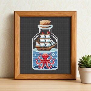 May include: A cross-stitch pattern of a glass bottle with a cork stopper. Inside the bottle is a small sailboat and an octopus with red tentacles.