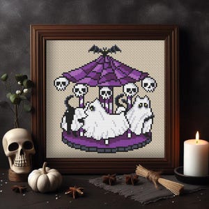 May include: Cross-stitch artwork in a wooden frame depicts a Halloween-themed carousel. The carousel features white ghost figures, skull accents, and a purple canopy with a bat on top. The artwork is displayed with a skull, pumpkin, and candle.