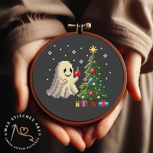 May include: A cross stitch pattern featuring a friendly ghost decorating a Christmas tree with a red bauble. The design is on a black background with white snowflakes.