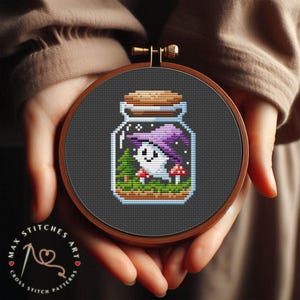 May include: A cross stitch pattern of a ghost wearing a purple hat inside a glass jar with a cork lid. The jar is filled with green grass, a small tree, and red and white mushrooms.