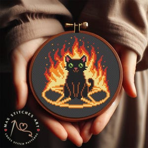 May include: Cross-stitch art featuring a black cat with green eyes, surrounded by flames. The design is set in a wooden embroidery hoop. The text "MAX STITCHES ART" and "CROSS STITCH PATTERNS" is visible.