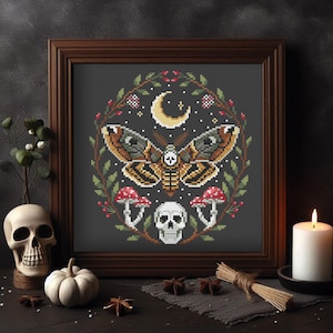 May include: Cross-stitch pattern featuring a moth with a skull and mushrooms in a wreath of leaves and berries on a dark gray background.