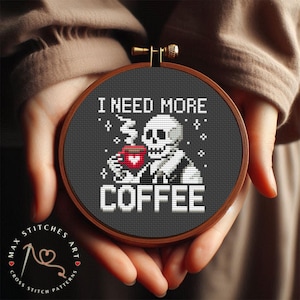 以下が含まれることがあります： 「I NEED MORE COFFEE」というテキストと共に、コーヒーカップを持ったスケルトンを描いた白黒のクロスステッチパターンです。