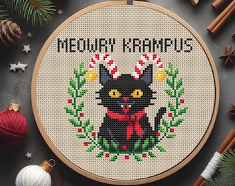 Könnte beinhalten: Kreuzstich-Stickerei in einem Holzrahmen zeigt eine schwarze Katze mit Zuckerstangen-Hörnern und einem roten Schal, umgeben von einem grünen Kranz. Der Text "MEOWRY KRAMPUS" ist über der Katze gestickt. Festliche Weihnachtsdekoration.