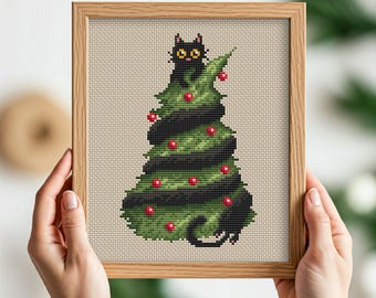 May include: A framed cross-stitch featuring a black cat inside a Christmas tree. The tree is green with black stripes and red ornaments. The cat has yellow eyes and is looking out from the top of the tree. The frame is made of wood.