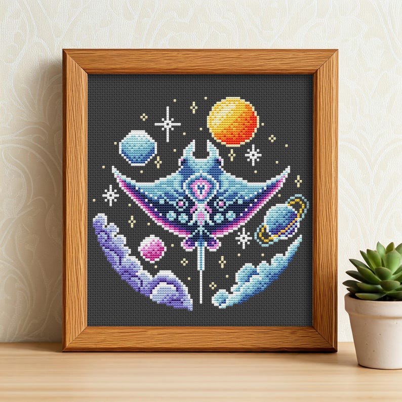 Puede incluir: Arte de punto de cruz de una manta raya estilizada en un marco de madera. El dise&ntilde;o presenta una manta raya azul y morada con un tema celestial, que incluye planetas, estrellas y un sol. El fondo es gris oscuro.