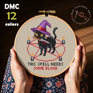 Pode incluir: Bordado em ponto cruz num bastidor de madeira com um gato preto com um chapéu de bruxa roxo, segurando uma faca e rodeado por um pentagrama vermelho. O texto "THIS SPELL NEEDS SOME BLOOD" está em baixo. 12 cores.