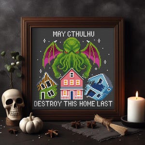 Puede incluir: Un patrón de punto de cruz con un monstruo verde con tentáculos y alas rojas, etiquetado como "May Cthulhu Destroy This Home Last". El monstruo está situado encima de tres casas, una verde, una rosa y una azul.