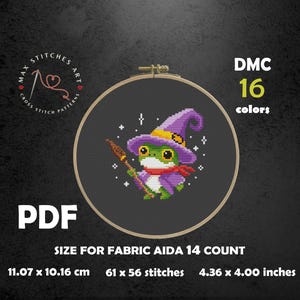 May include: Cross-stitch pattern featuring a green frog wearing a purple witch hat and scarf, holding a broom. The design is set in a wooden embroidery hoop. The text "DMC 16 colors" and "PDF" are included. The pattern size is 4.36 x 4.00 inches.