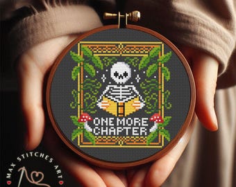May include: A black and white cross stitch pattern of a skeleton reading a book with the text "One More Chapter" in a green and yellow frame.