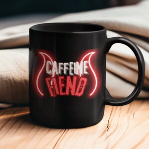 Puede incluir: Taza de café de cerámica negra con un diseño de neón rojo que dice "Caffeine Fiend".