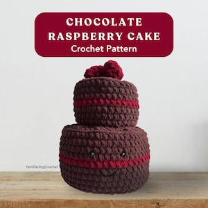 May include: A two-tiered, crocheted chocolate raspberry cake with a smiling face and red accents. The cake has a dark brown color with a red stripe around each tier and a cluster of red raspberries on top. The text "CHOCOLATE RASPBERRY CAKE Crochet Pattern" is at the top.