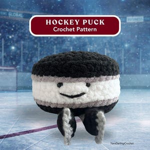 May include: A crocheted hockey puck with a smiling face and small legs. The puck is black, white, and gray, with the text "HOCKEY PUCK Crochet Pattern" in a red banner above. The background is a hockey rink.