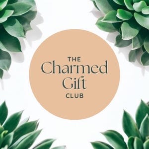 May include: A circular logo with the text "THE Charmed Gift CLUB" in dark gray against a peach background. Green succulent plants are in the corners of the image, set against a white background.