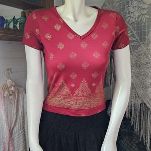 May include: A red short-sleeved shirt with a gold floral pattern and a black lace skirt.