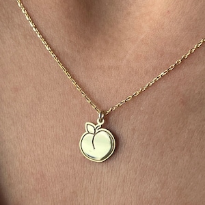 May include: A gold chain necklace with a peach charm pendant.