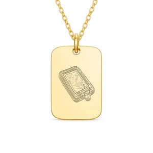 May include: Gold-colored pendant necklace featuring a rectangular dog tag pendant. The pendant has a detailed engraved design of a handheld device. The necklace chain is also gold-colored.