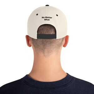 May include: A beige and black baseball cap with the text "No Matter What" embroidered on the back.