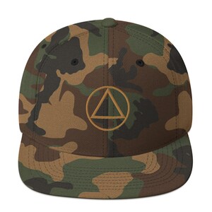 May include: A camouflage-patterned baseball cap with a gold embroidered triangle inside a circle. The triangle is split in half, with one half black and the other half white.