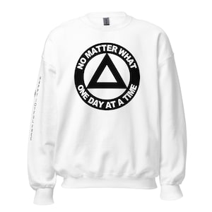 May include: White sweatshirt with a black circle and triangle graphic that says "No Matter What One Day At A Time". The left sleeve has the words "Happy Joyful Free" printed vertically.