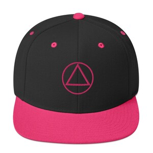 May include: A black and pink baseball cap with a pink circle and triangle design. The cap has a flat brim and a curved crown.